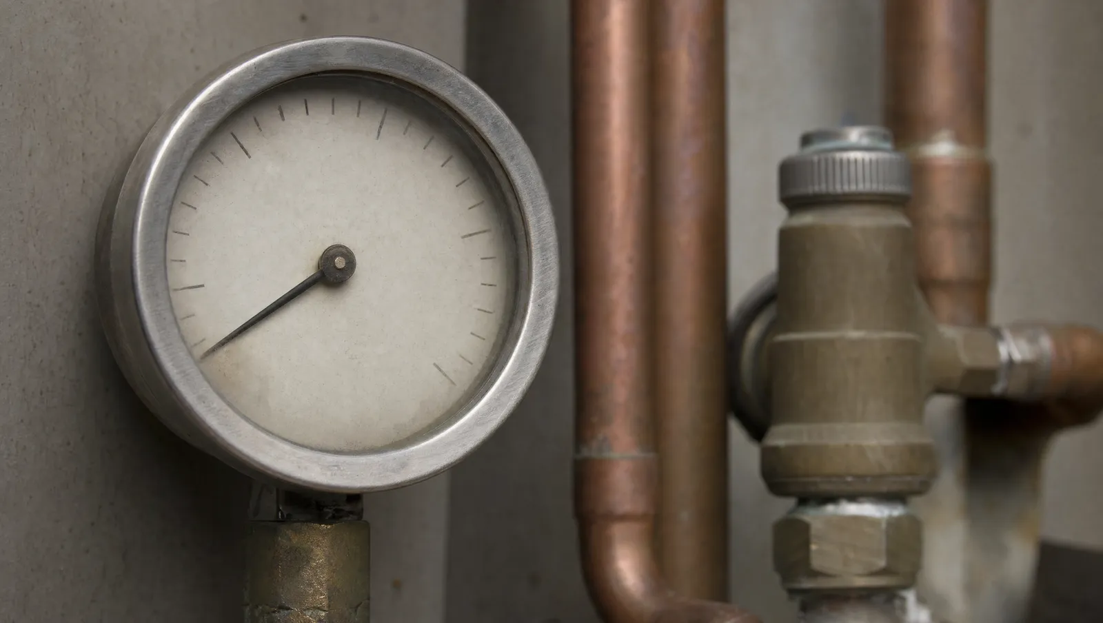 Macro of a domestic boiler pressure gauge with copper pipework behind it